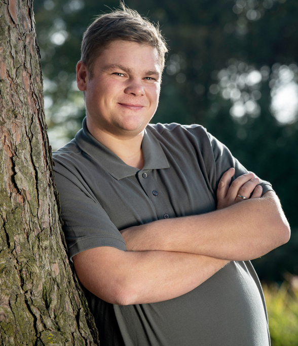 Kollege lehnt am Baum